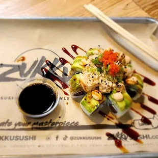 a plate of sushi with sauce and chopsticks