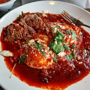 Huevos ranchero with shredded beef and red sauce.