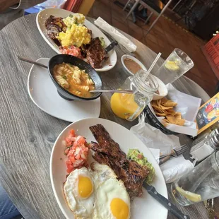 One plate is Chilaquiles with mole sauce and steak and eggs.  Other plate steak and eggs  with home made tortillas