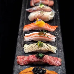 a variety of sushi on a black plate