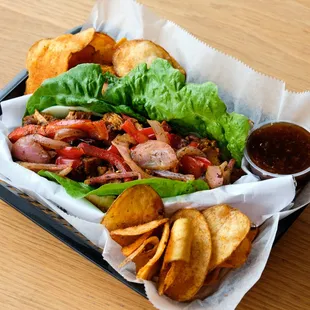 a sandwich with lettuce, meat, and chips