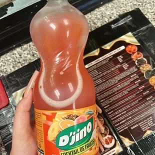 a person holding a bottle of orange juice