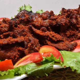 a plate of meat with lettuce and tomatoes