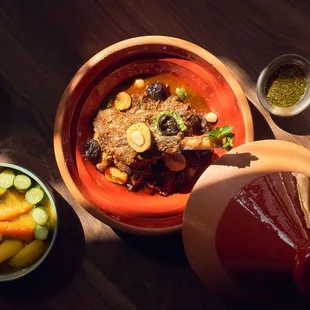 a bowl of stew, a bowl of rice, a bowl of fruit, and a bowl of bread