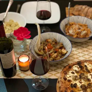 a table with a pizza, wine, and a candle