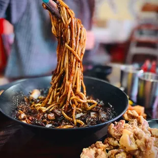 a person holding a fork full of noodles